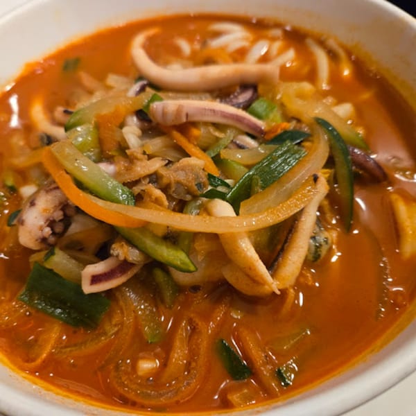 A close-up of Kimchi House's Jjamppong, a spicy Korean seafood noodle soup with squid and vegetables.