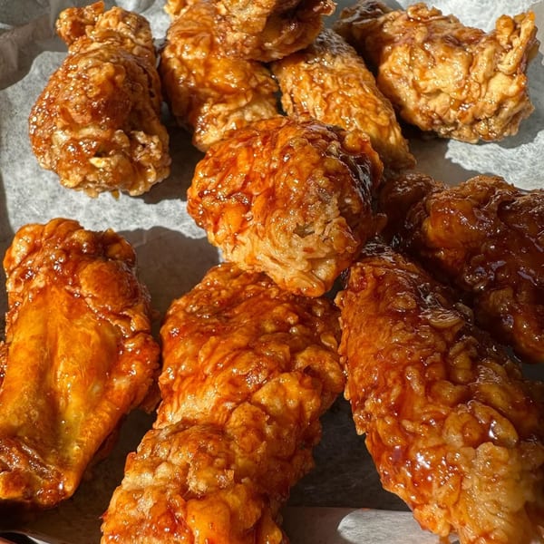 Close-up of several golden-brown Korean fried chicken wings coated in a glossy, sweet, and spicy sauce.